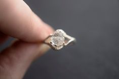 a close up of a person's hand holding a ring with a diamond in it