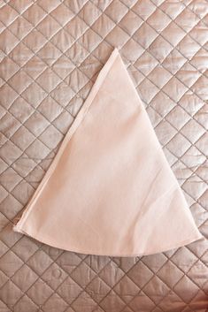 a white cloth triangle on top of a quilted bed spread with the corner folded up