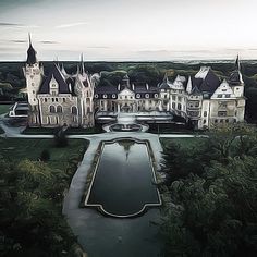 an aerial view of a castle with a pond in the foreground