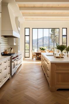 a large kitchen with wooden floors and white cabinets, windows overlooking the mountains is shown