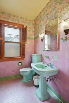 a bathroom with pink and green walls, toilet, sink and window in the corner