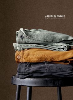 three pairs of jeans stacked on top of each other in front of a brown background