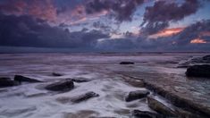 some rocks water and clouds at sunset