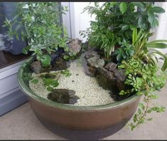 a large potted planter filled with rocks and plants next to a glass door