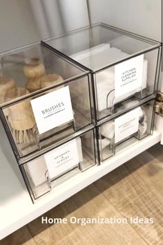 three clear boxes with labels on them are sitting on a shelf in front of a mirror