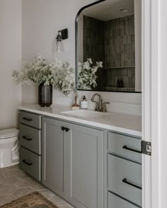 a bathroom with gray cabinets and white flowers