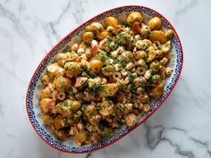 a bowl filled with food sitting on top of a marble countertop next to a knife and fork