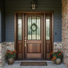 a front door with two planters and a wreath on it