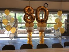 balloons are hanging from the ceiling in front of a table with chairs and large numbers