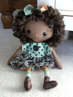 a little doll with curly hair sitting on the floor