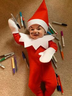 an elf is laying on the floor with crayons all around him