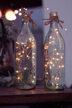 two bottles with lights in them sitting on a table