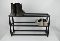 two pairs of shoes are sitting on a black shoe rack against a white background with copy space