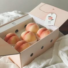 four peaches in a box on a bed