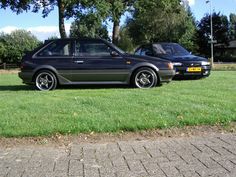 two cars parked in the grass next to each other