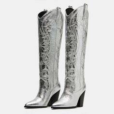 Glimmer in the spotlight with these metallic embroidered knee-high cowgirl boots in silver. The intricate details and heeled design make them a shining statement piece for any outfit. Color: Silver Material: Metallic finish Heel Type: Block heel Heel Height: 3.66'' /93 mm approx Product measurements were taken using size 8. Please note that measurements may vary by size. Toe: Pointed toe Metallic finish design Embroidered design Pull-on design Handcrafted US sizing. Fits true to size. Glamorous Silver Knee-high Boots, Western Style Knee-high Party Heeled Boots, Western Style Knee-high Heeled Boots For Party, Silver Fitted Snip Toe Boots, Fitted Silver Glamorous Knee-high Boots, Silver Fitted Pointed Toe Heeled Boots, Silver Fitted Heeled Boots With Pointed Toe, Elegant Silver Snip Toe Boots, Silver Fitted High Heel Boots