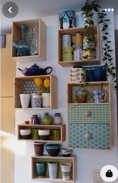 several wooden shelves with pots, pans and cups on them hanging from the wall