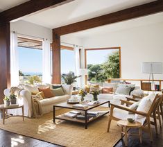 a living room filled with lots of furniture next to large windows and wooden flooring