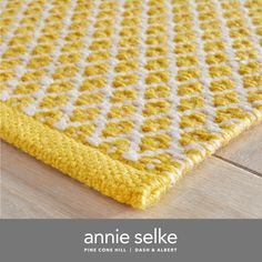 a yellow and white rug on the floor with text that reads annie selke