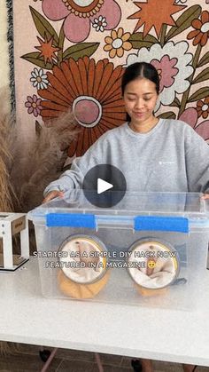 a woman standing behind a plastic box filled with doughnuts