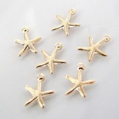 five small gold starfish charms on a white surface