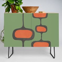 a green cabinet with an orange design on it and a potted plant next to it