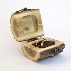 two wedding rings in a wooden box on top of a white surface with the lid open