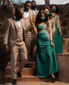 a group of people in formal wear standing on steps with one woman wearing a green dress