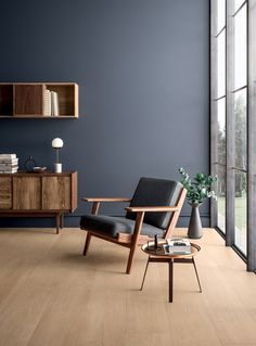 an empty living room with blue walls and wooden furniture in the corner, along with large windows