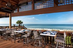 an outdoor dining area with tables and chairs overlooking the ocean