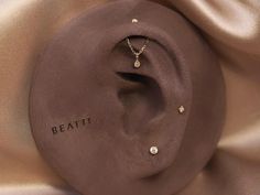 a brown hat with the word beati written on it and two diamond studs