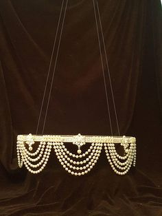 a chandelier with pearls hanging from it's sides on a black velvet background