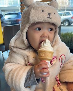 a small child in a bear costume eating an ice cream cone with candy canes