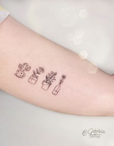 a woman's arm with three small vases and flowers on the left forearm