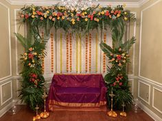 an altar decorated with flowers and greenery in front of a chandelier hanging from the ceiling