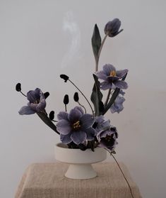 a white vase with purple flowers in it