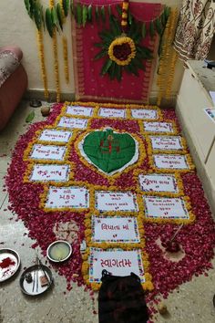 a decorated table with flowers and candles on the ground in front of a red wall