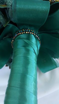 a close up of a green ribbon with beads on it's end and some flowers in the background