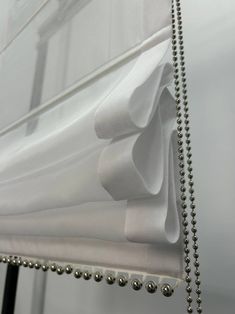 a white curtain with silver beads hanging from it's side and the curtains are closed