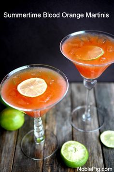 two cocktails with orange and lime garnish in coupe glasses on a wooden table