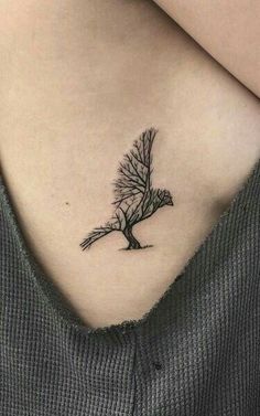 a woman's chest with a small tree tattoo on it