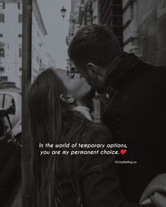 a man kissing a woman on the cheek in front of a city street with cars