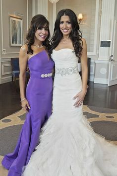 two women standing next to each other in formal wear posing for the camera with their arms around each other