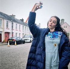 a woman in overalls holding up a toothbrush