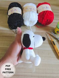 a hand holding a stuffed dog next to crochet supplies