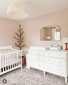 a baby's room with a crib, dresser and mirror on the wall