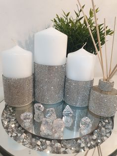 three white candles sitting on top of a glass table next to crystal rocks and reeds