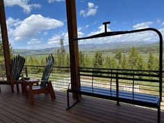 two chairs sitting on top of a wooden deck next to a metal rail and railing