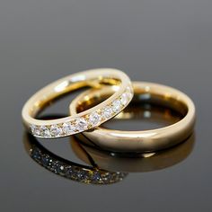 two gold wedding rings sitting on top of each other