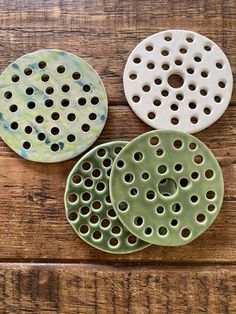 three ceramic plates sitting on top of a wooden table next to each other with holes in them